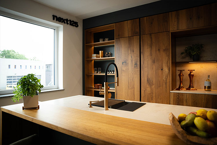 Moderne Küchenzeile mit Holzregalen, Spüle und Obstschale auf der Arbeitsfläche.