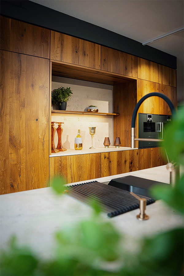 Küchenzeile mit Holzregal, dekoriert mit Flaschen und Gläsern.